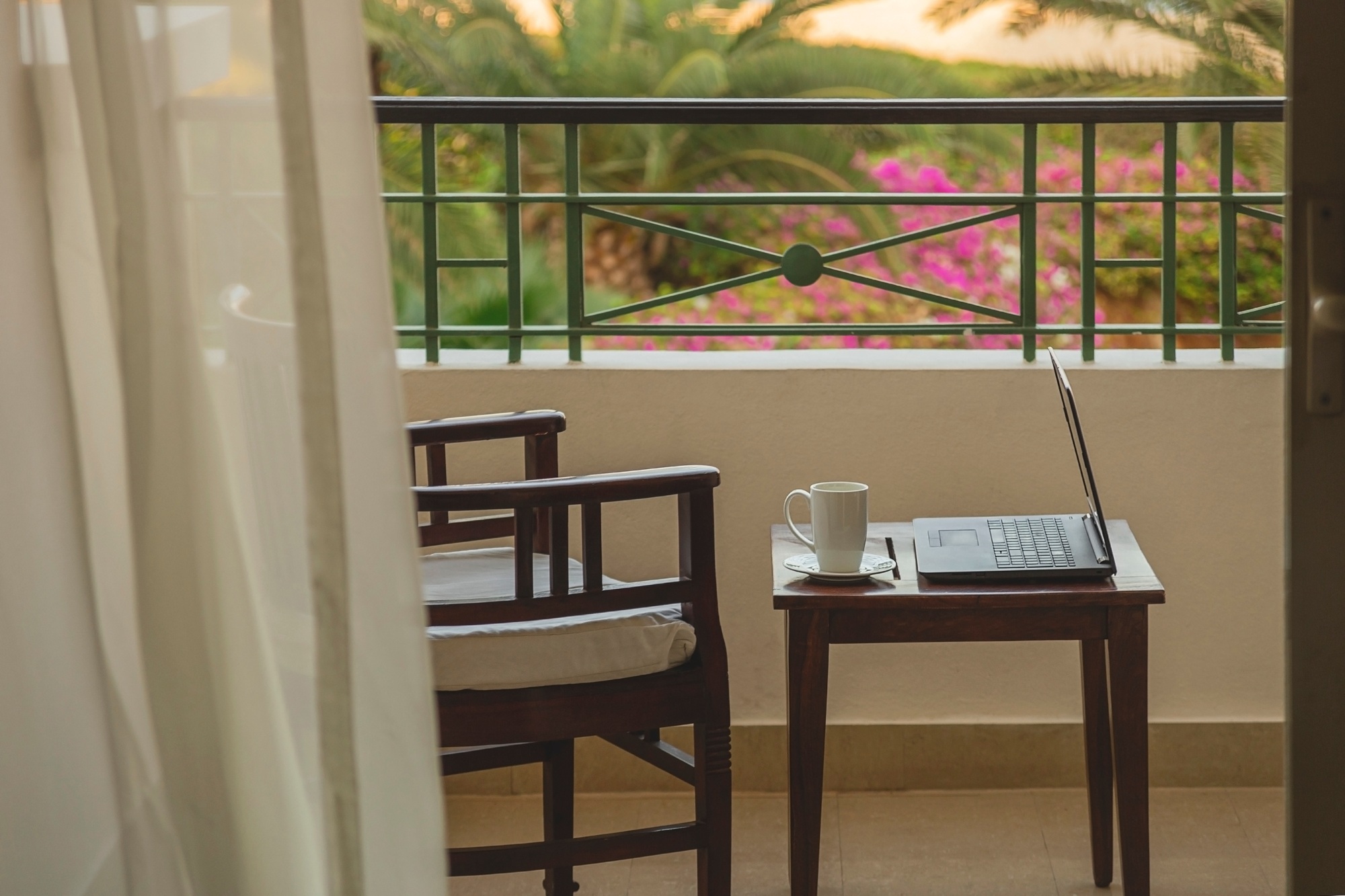 Freelancer or businessman working remotely with laptop on hotel balcony at resort while traveling.