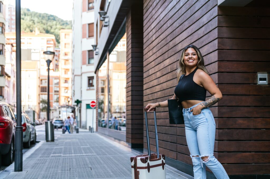 Radiant Latin Beauty Exiting City Hotel with Stylish Travel Trolley