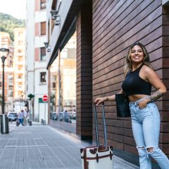 Radiant Latin Beauty Exiting City Hotel with Stylish Travel Trolley